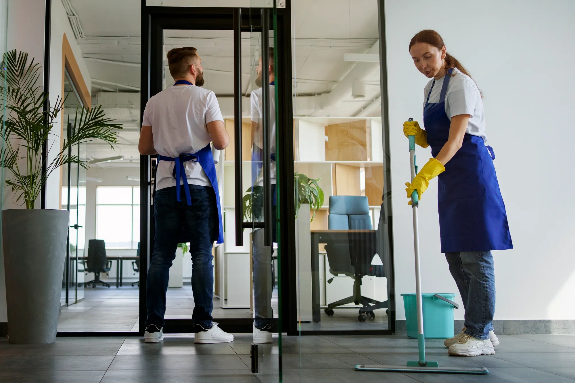 Two professional cleaners working together in a commercial office space